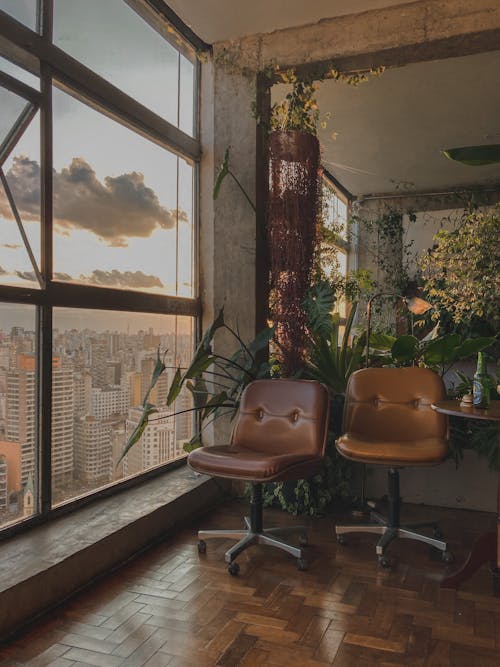 Brown Leather Office Rolling Chairs beside Glass Window