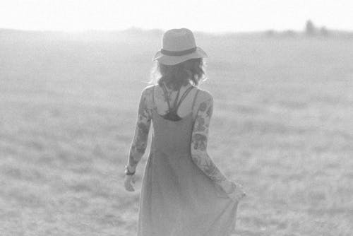 Free Woman in Spaghetti Strap Dress Walking on a Field in Grayscale Photography Stock Photo