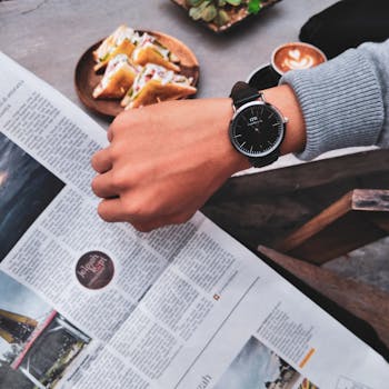 Close-up of a stylish watch on a wrist with breakfast and coffee at a café.