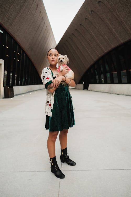 Free A Woman in Green Dress Carrying a Shih Tzu while Looking Afar Stock Photo