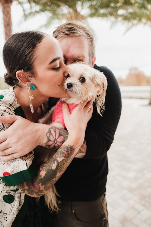 

A Couple Hugging and Kissing Their Pet Dog