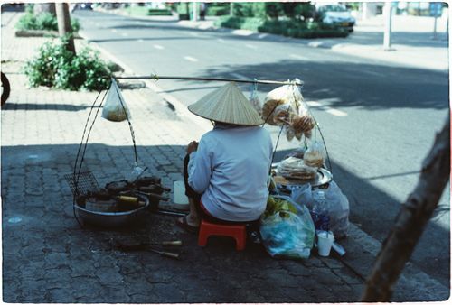 Free Street vendor with conical hat selling food on a sidewalk in Ho Chi Minh City, Vietnam. Stock Photo