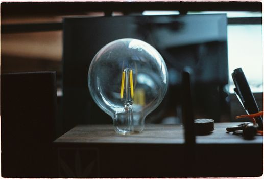 A detailed close-up of a traditional light bulb placed on a workbench in a workshop, showcasing its transparency and structure.