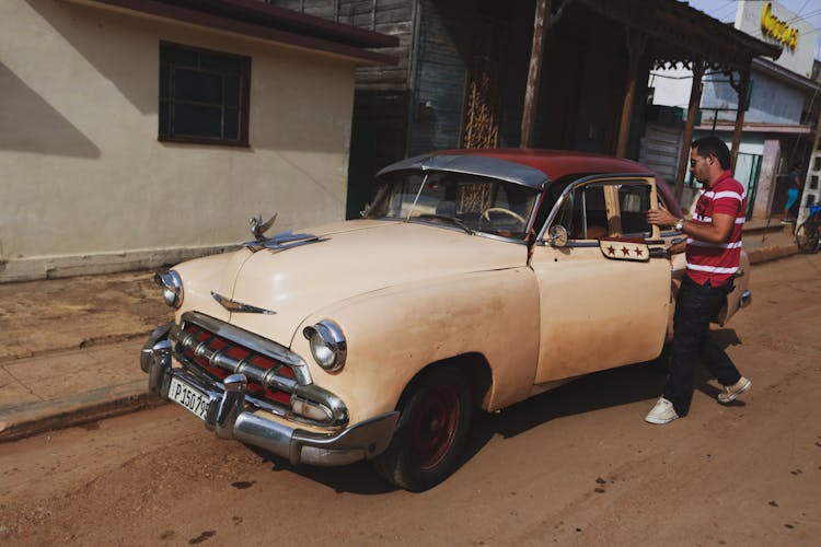 Man Opening The Door Of A Vintage Car Parked On Road