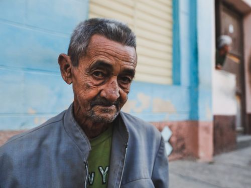 Free Close-up of an elderly man with wrinkles in a street setting, showcasing life's experiences. Stock Photo