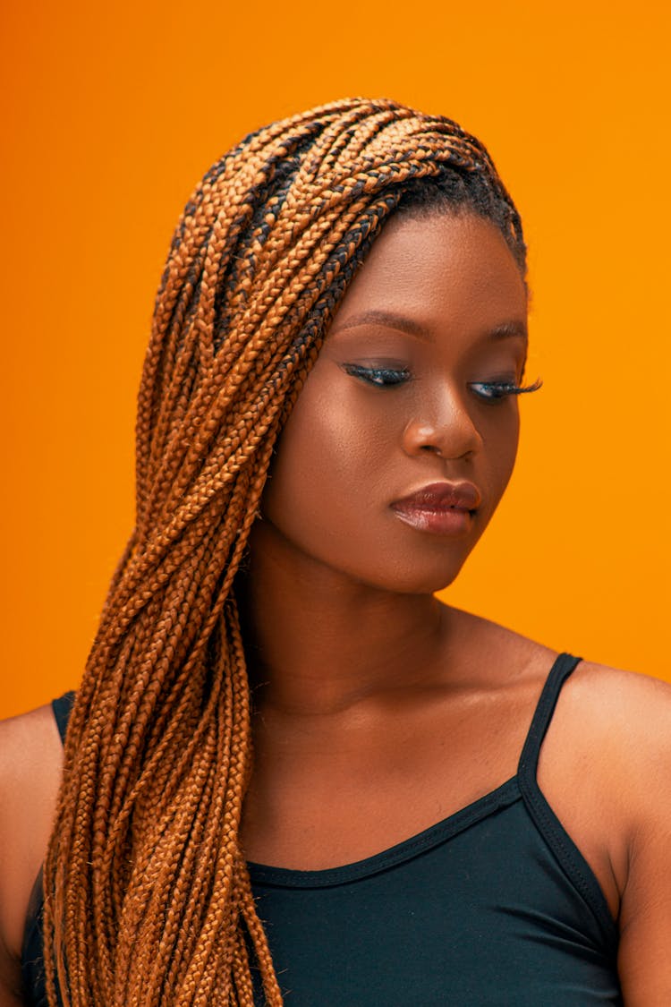 Portrait Of Woman In Long Box Braids On Orange Background