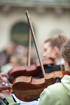 A close-up view of violinists playing in an outdoor performance, showcasing musical passion.