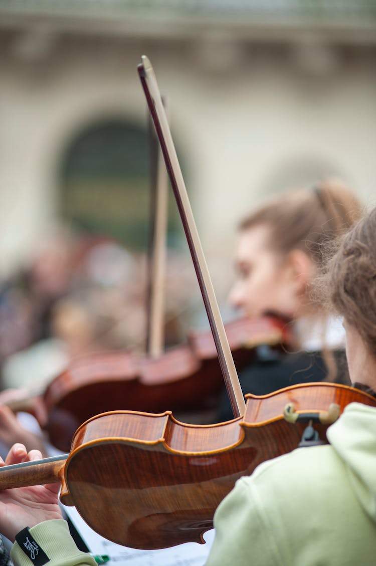 Close-up Of People Playing On Violins