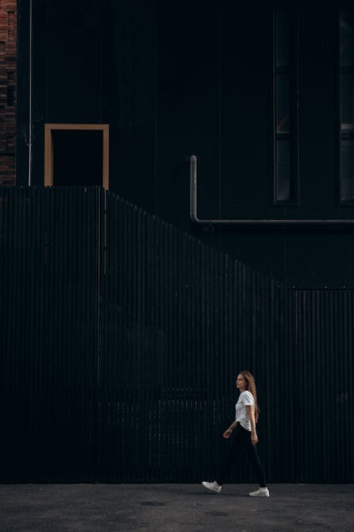 Woman Walking Past Black Building