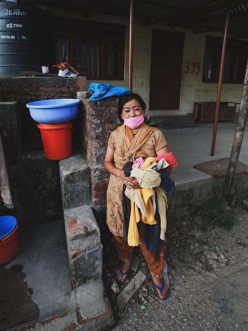 Woman with Pink Medical Mask Holding Laundry