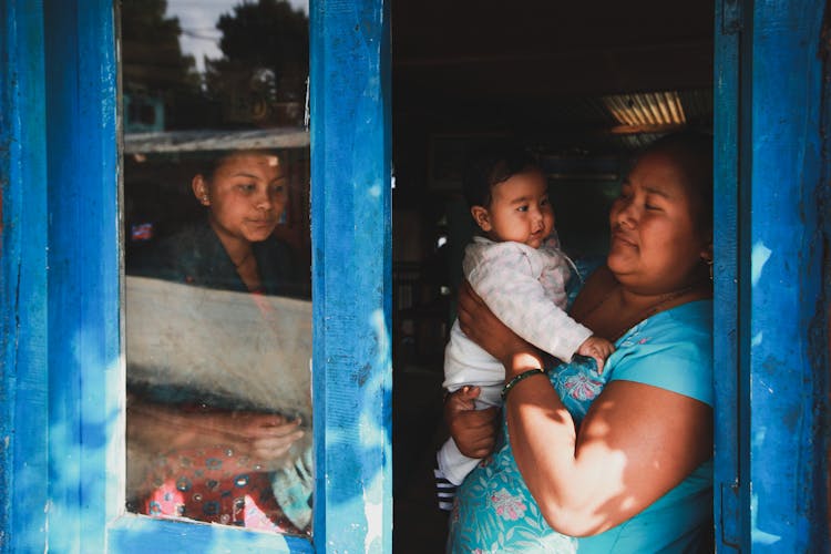 Women Standing In Open Window With Baby Boy