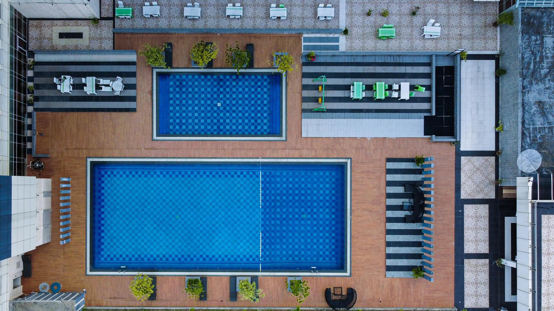Aerial view of a modern pool area in Riau Islands, Indonesia, showcasing geometric design and blue water.
