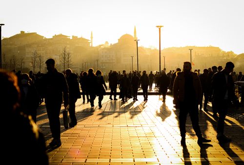 Free Silhouetted people walking through a sunlit park in Istanbul, capturing the vibrant city atmosphere. Stock Photo