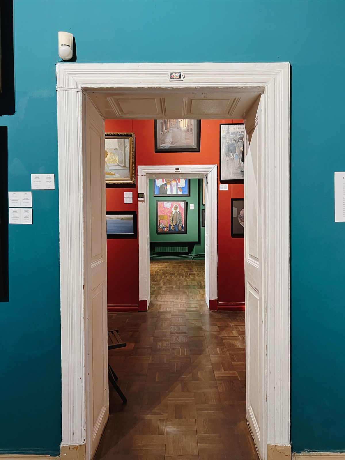 A gallery interior with paintings on coloured walls
