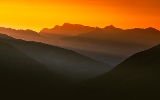 Dramatic mountain landscape with an orange sky at sunrise, perfect for nature enthusiasts.