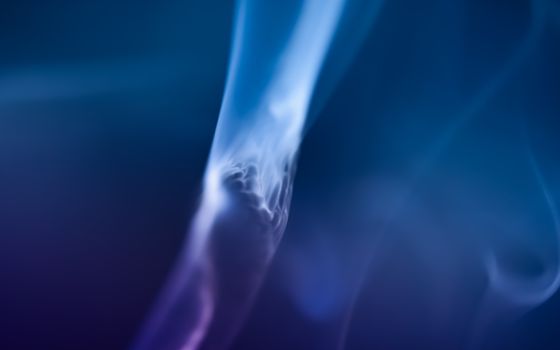 A captivating abstract image of blue smoke swirling gracefully against a dark background.