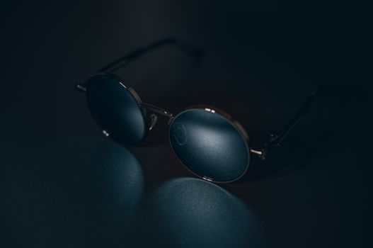 Close-up of stylish sunglasses on a dark surface with reflection, showcasing elegance and fashion.