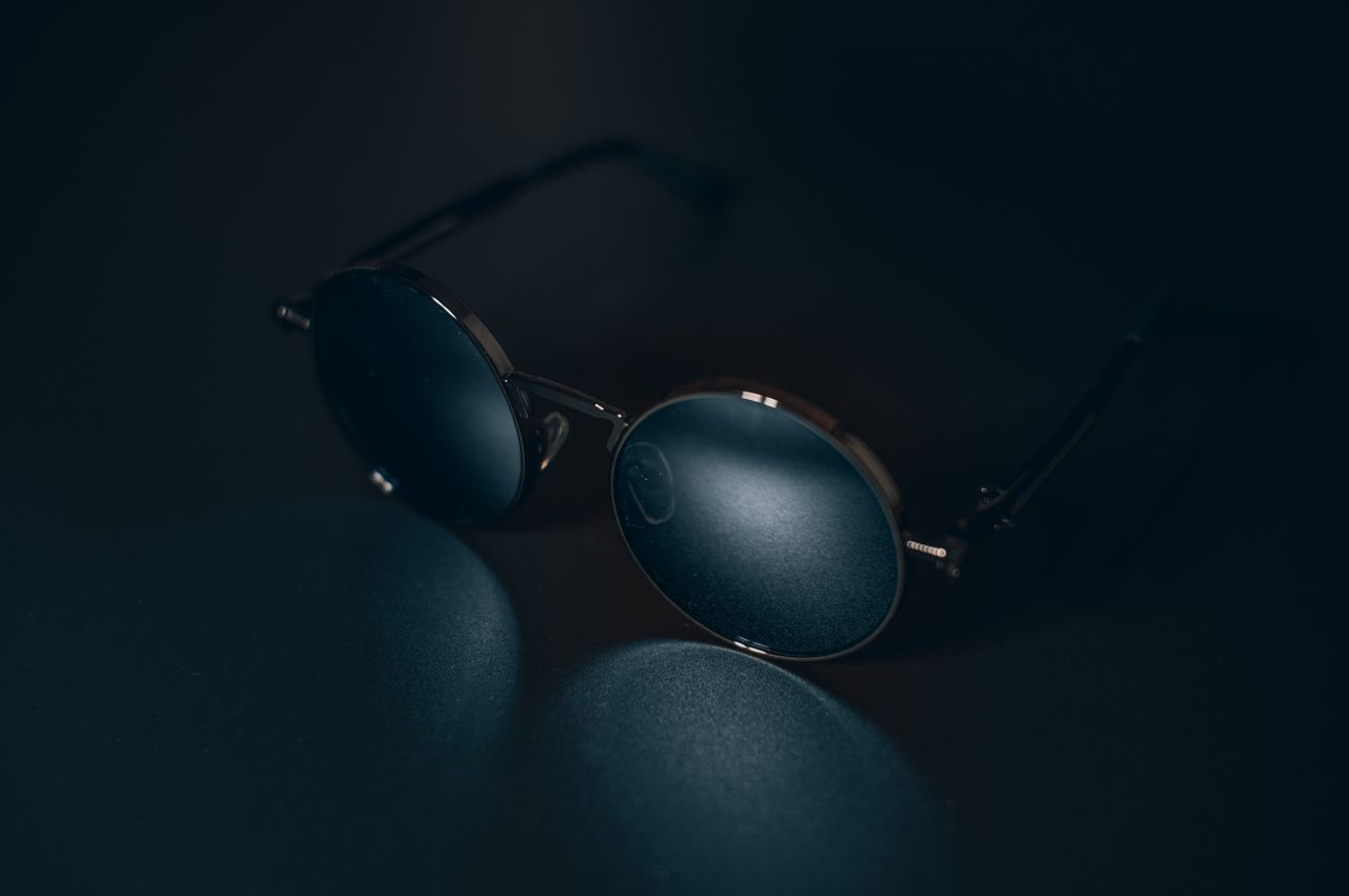 close up of stylish sunglasses on a dark surface with reflection showc