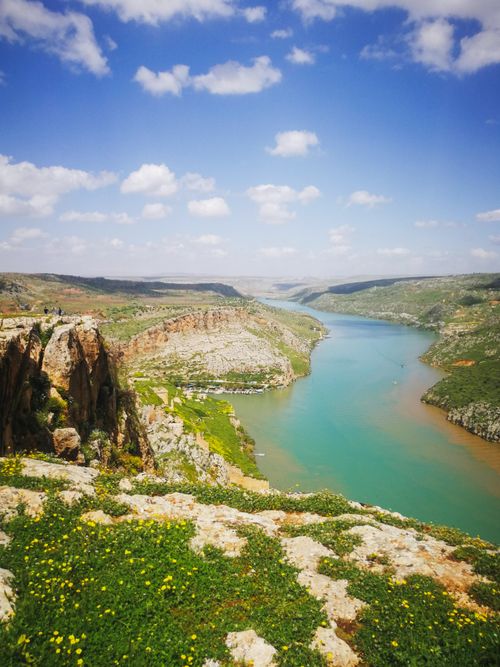 Free A breathtaking aerial view of a river winding through a lush, hilly landscape under a blue sky and scattered clouds. Stock Photo