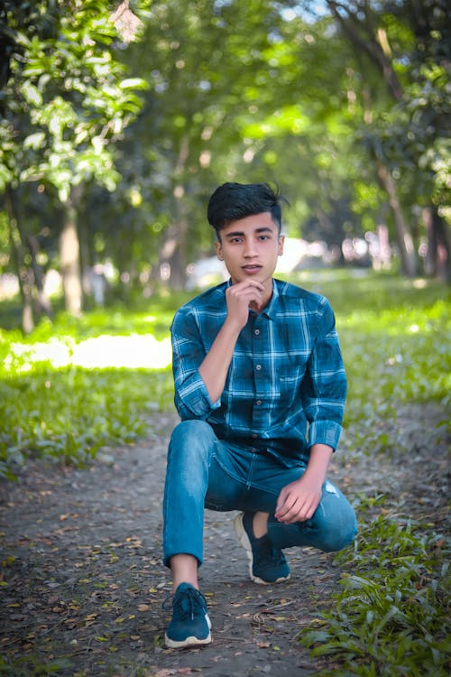 Teenage Boy in Blue Long Sleeves and Pants Sitting on Pathway