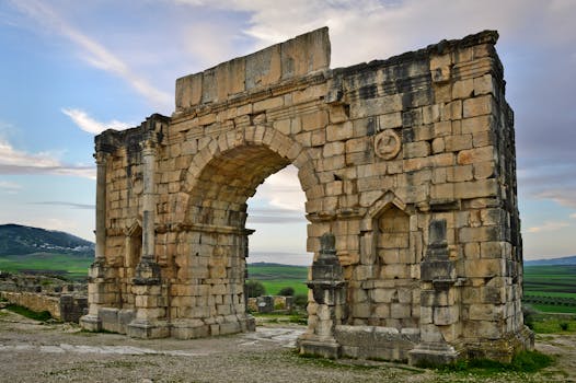 Stunning view of the ancient Roman arch in Volubilis, Morocco amid a serene landscape.
