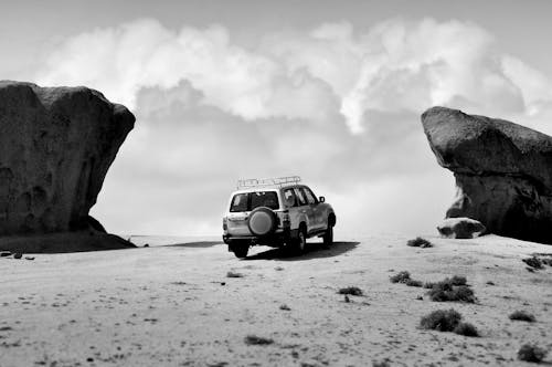 Vehicle Parked on Desert Land Between Two Rocks