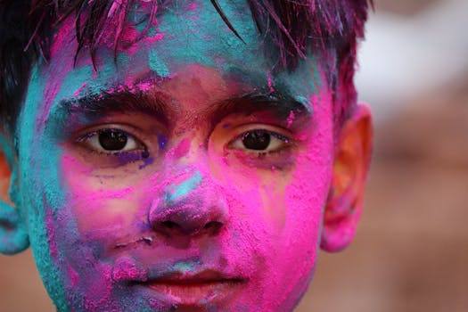Close-up portrait of a young man with colorful face paint during Holi festival, expressing joy and cultural celebration.