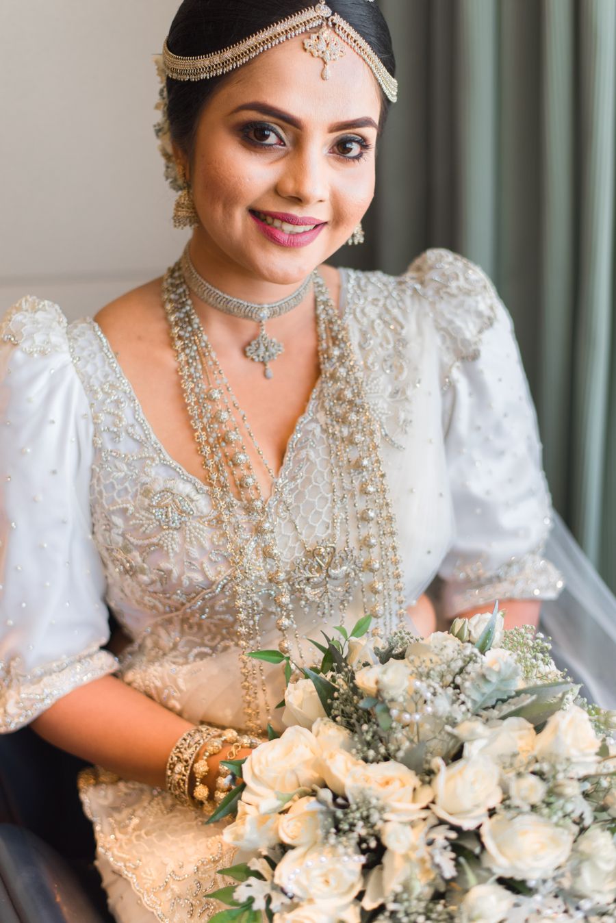Smiling Kandyan bride with matha patti, silver chains and bridal bouquet