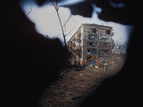 A damaged building in Kyiv, Ukraine, with surrounding destruction and machinery, showcasing urban conflict aftermath.