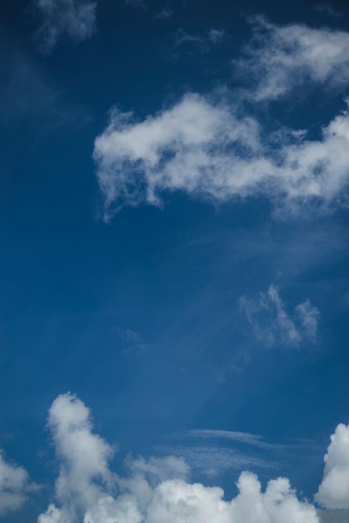 Free Serene image of a clear blue sky adorned with fluffy clouds on a sunny day. Stock Photo