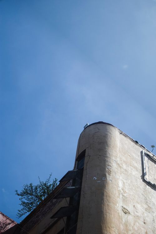 Free Low-angle view of an old building corner against a bright blue sky, offering clear copy space. Stock Photo