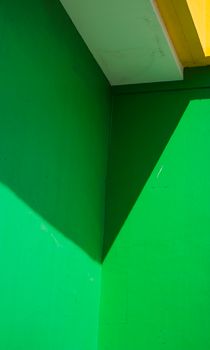 Vibrant abstract image of a green wall with dynamic shadows and geometric shapes.