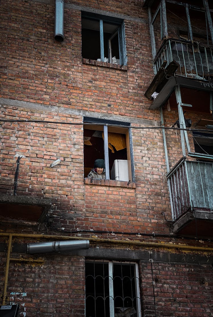 A Person Peeking At The Window Of A Brick Building