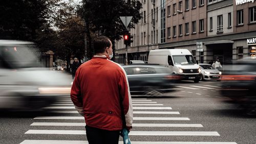 Free Man in red jacket at a busy pedestrian crossing in Riga, Latvia during the day. Stock Photo