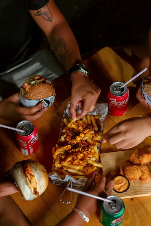 People Eating French Fries on Brown Wooden Table