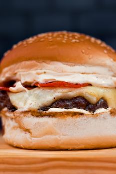 Close-up of a delicious cheeseburger with fresh toppings on a wooden board.