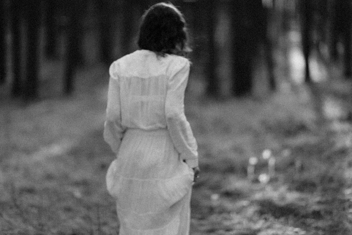 Woman in White Long Sleeve Dress Standing on Grass Field