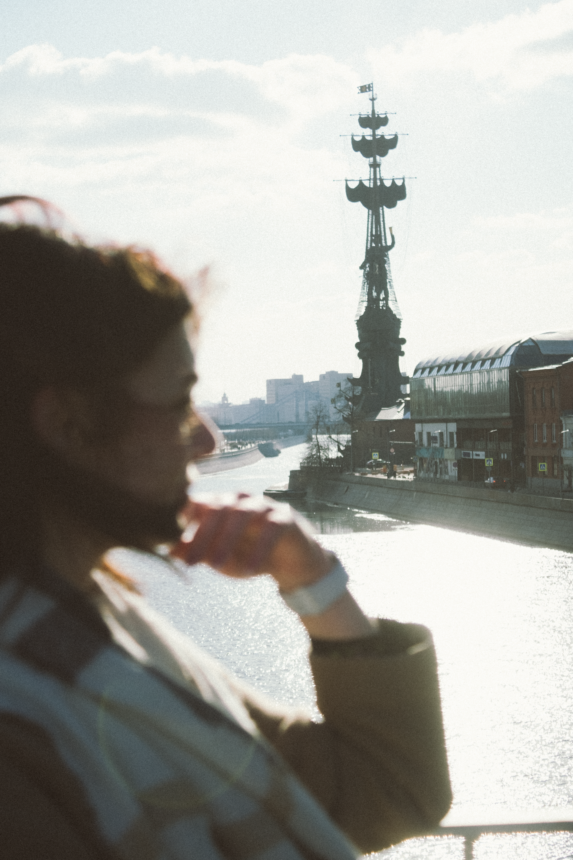 Silhouette of a woman looking over a riverside city with a large ship monument.