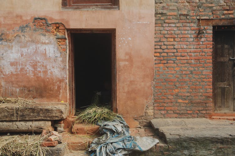 Piles Of Hay In Front Of Brick House