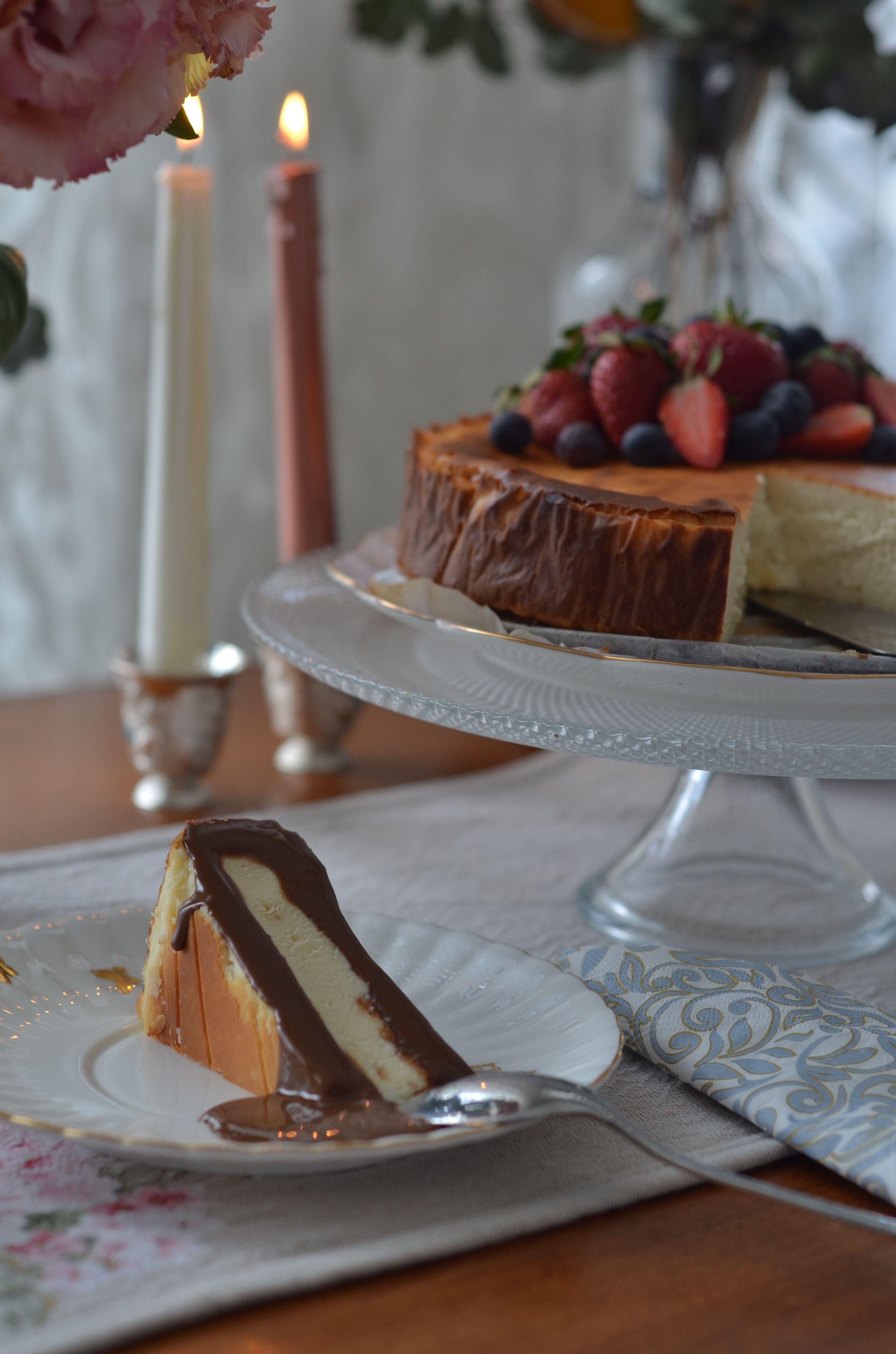 Delicious cheesecake slice with chocolate sauce, surrounded by elegant decor on a wooden table.