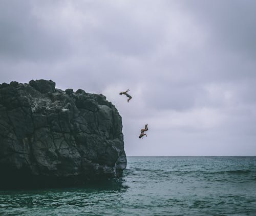 Two People Jumping on Body of Water