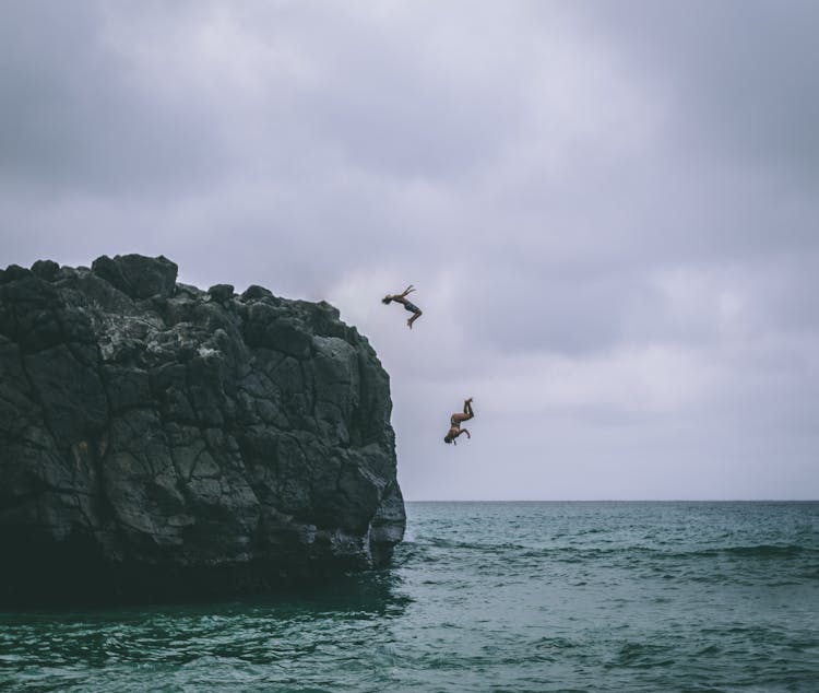 Two People Jumping On Body Of Water