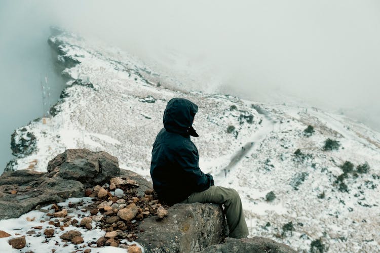 Woman Sitting On Rock On Top Of Mountain