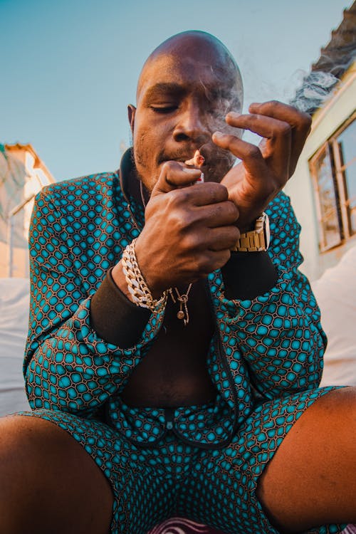 A Man Wearing Jewelries Lighting Up a Cigarette