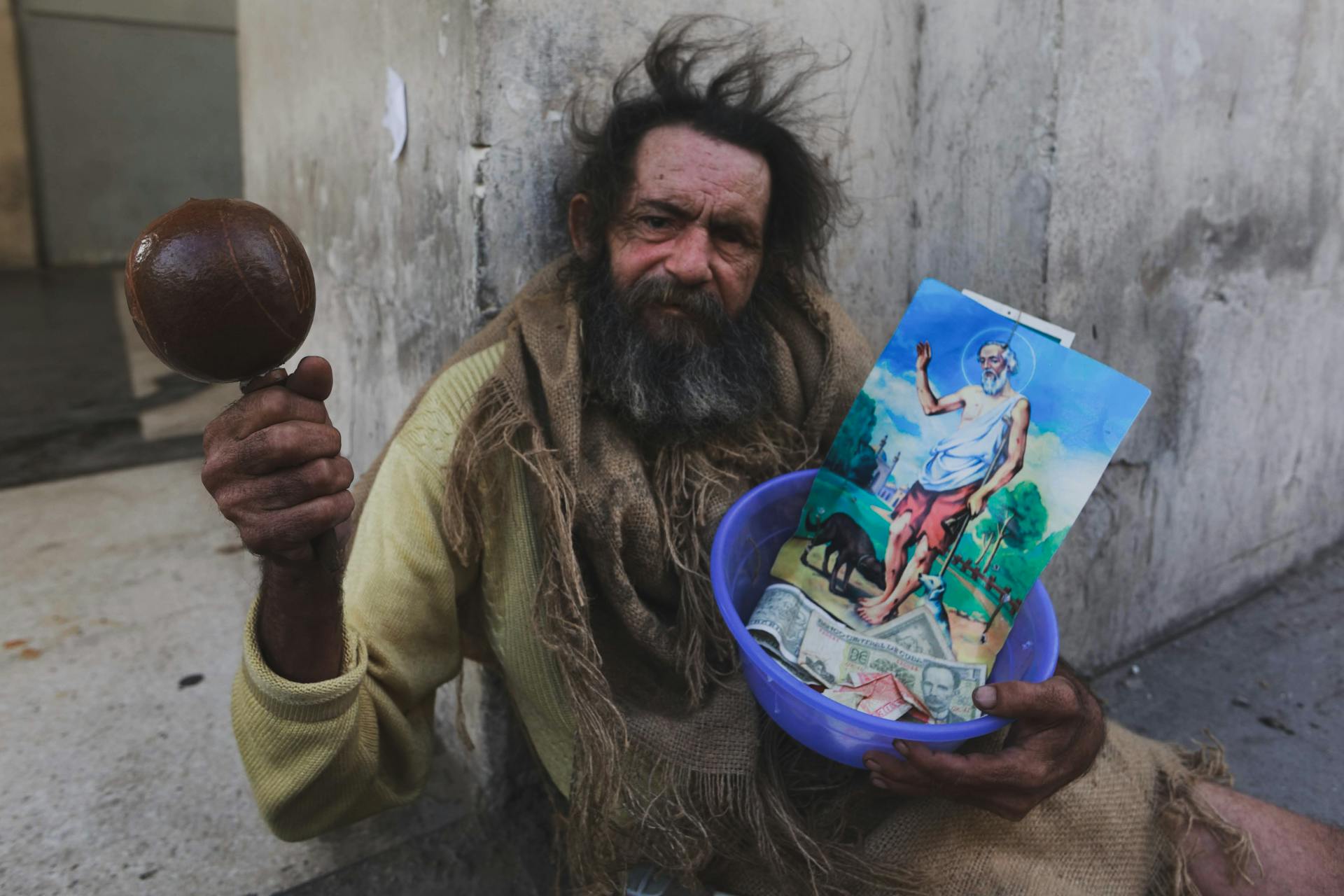 Man Sitting by Wall with Ball and Bowl with Picture and Money