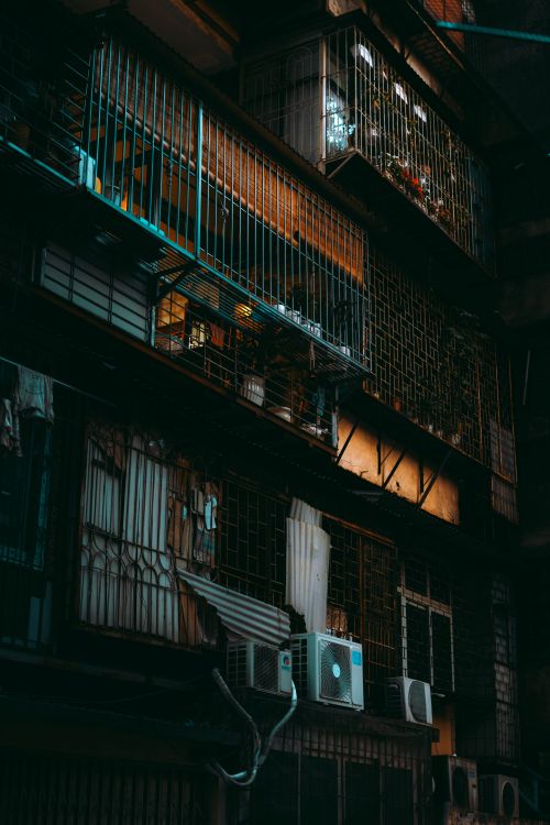 Free Illuminated urban residential building showcasing balconies and windows at night. Stock Photo
