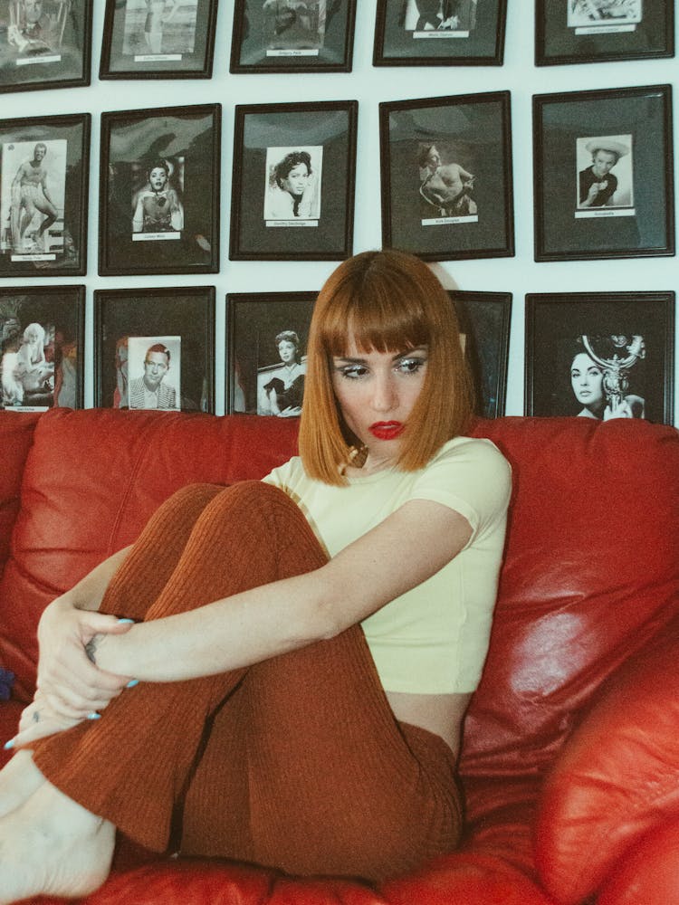 Portrait Of A Redhead Woman In White Shirt Sitting On Red Couch