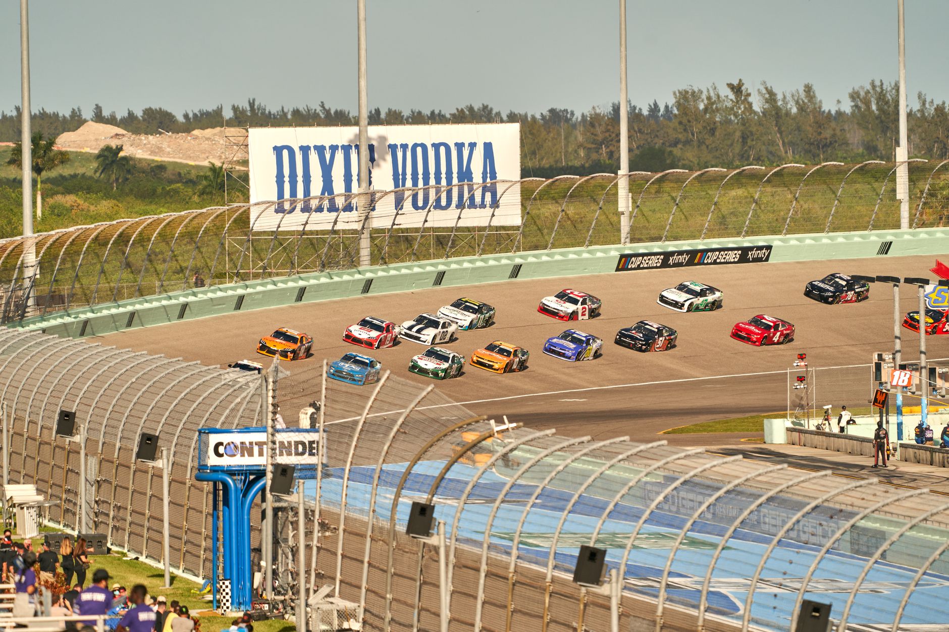 High-speed NASCAR race on a sunny day at the iconic Miami speedway track.