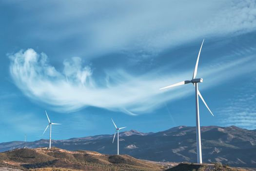 White Wind Turbine on Brown Field Under Blue Sky and White Clouds