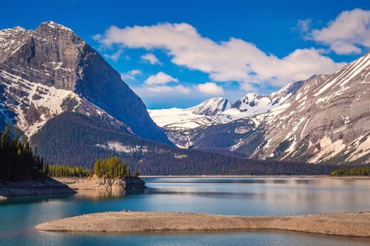Serene mountain lake surrounded by snow-capped peaks in Kananaskis, Alberta, Canada.